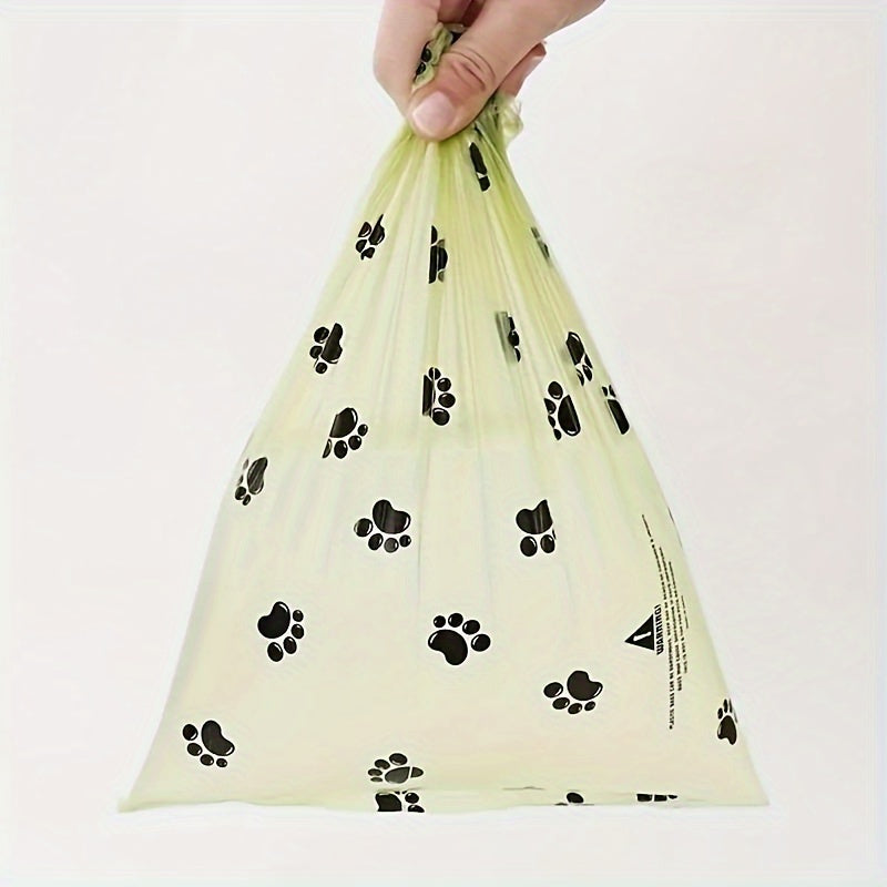 Hand holding a light yellow bag with black paw print patterns on a white background